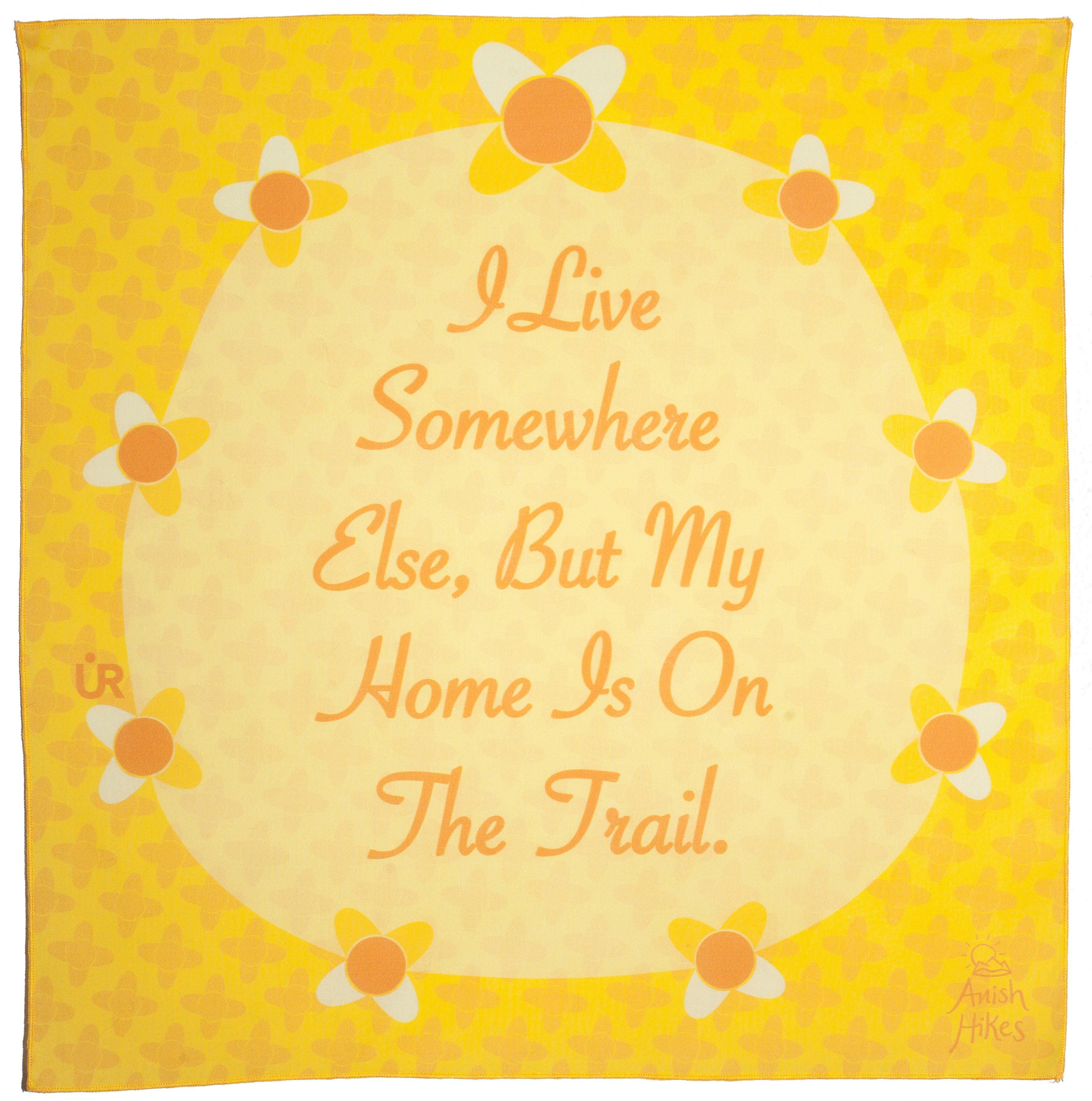 Anish Bandana UR Sportswear collaboration. Yellow bandana that has flowers around a circle. The bandana is inspirational and says, I live somewhere else, but my home is on the trail. A quote by Anish.