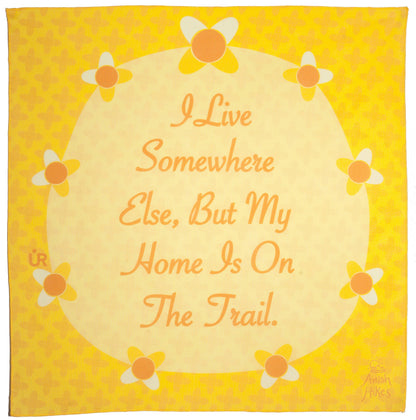 Anish Bandana UR Sportswear collaboration. Yellow bandana that has flowers around a circle. The bandana is inspirational and says, I live somewhere else, but my home is on the trail. A quote by Anish.